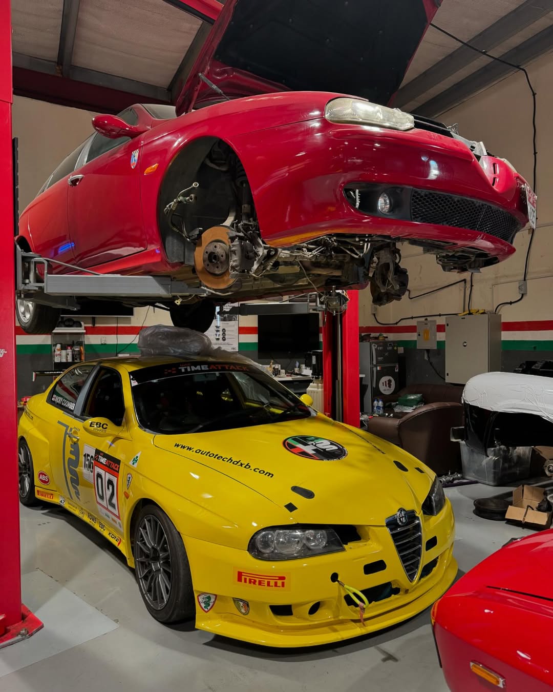 Classic Alfa Romeo on lift with heritage badge wall